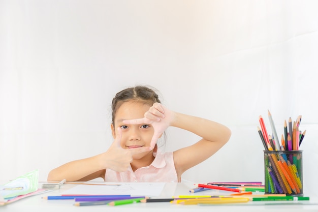 Menina mostra um quadro de mãos como foto, garoto desenho com lápis coloridos
