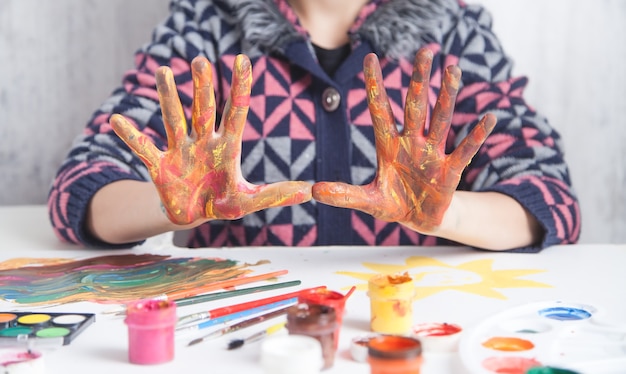 Foto menina mostrando as mãos com tinta multicolor. arte moderna. passatempo