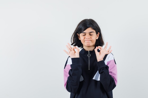 Menina mostrando gesto de meditação na camisa e parecendo relaxado. vista frontal.