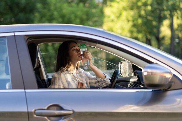 Menina motorista exausta, sofrendo de dor de cabeça, calor, clima quente e aplica garrafa de água na testa