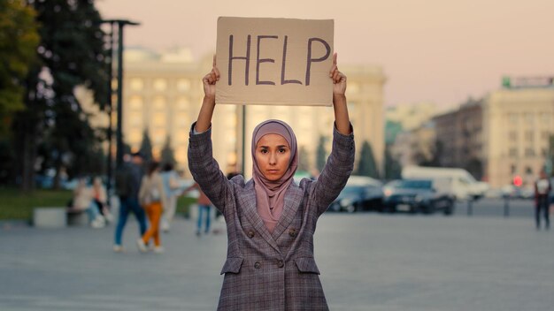 Menina muçulmana triste usa hijab mulher fica na cidade olhando para a câmera demonstra ajuda de texto de banner