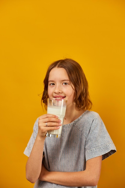 Menina muito adolescente com um copo de leite fresco