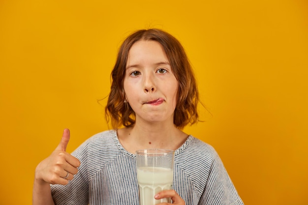 Menina muito adolescente com um copo de leite fresco