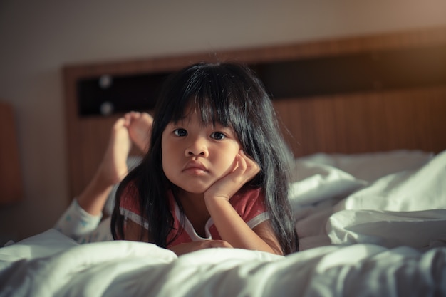 Menina muito agradável e adorável descansar na cama e assistir televisão