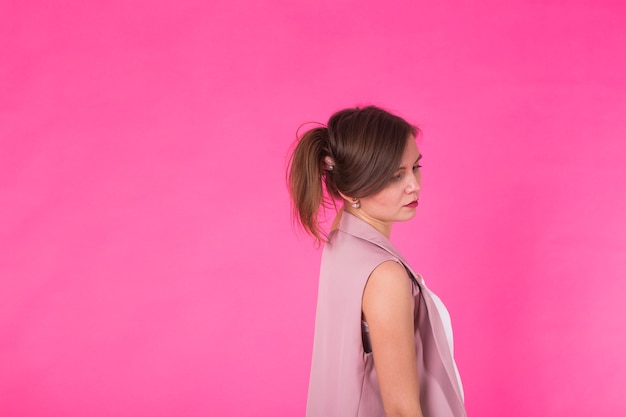 Foto menina muito elegante com cabelo comprido, posando contra um fundo rosa. retrato da moda de jovem feliz e sorridente