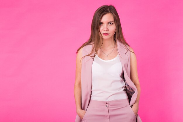 Menina muito elegante com cabelo comprido posando contra um fundo rosa