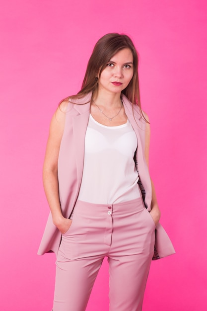 Menina muito elegante com cabelo comprido posando contra um fundo rosa