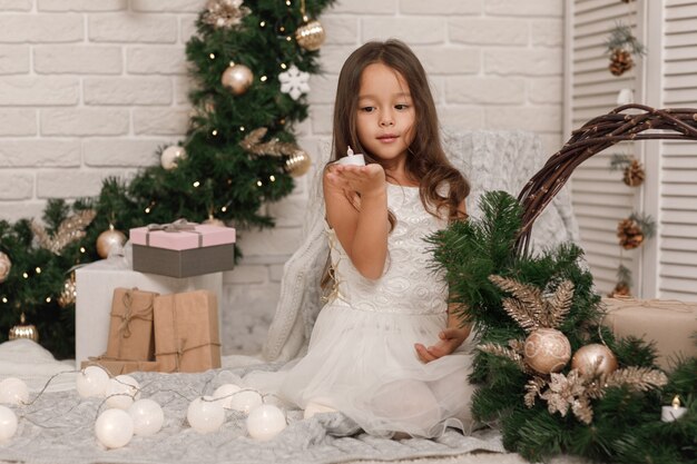 Menina muito sorridente decorando a árvore de Natal em casa