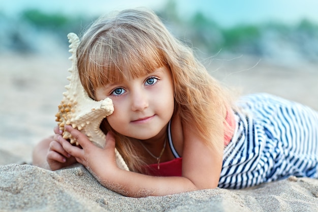 Menina na areia com uma estrela do mar