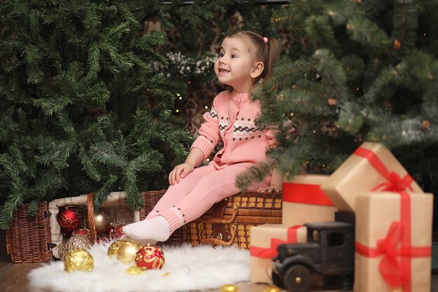 Menina na atmosfera de Natal de ano novo. A menina está feliz com o Natal e os presentes. Uma criança na árvore de ano novo com presentes.