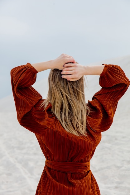 Menina na blusa da cor de Borgonha em um brach branco da areia.