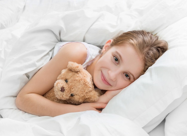 Foto menina na cama com ursinho de pelúcia, adormecer