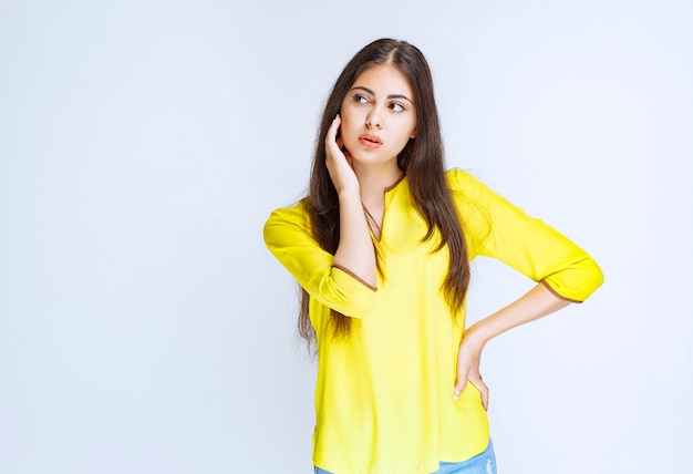 Menina na camisa amarela pensando e brainstorming.