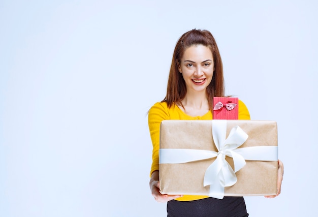 Menina na camisa amarela segurando caixas de presente e dando ao cliente.