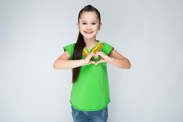 Menina na camiseta verde e calças de ganga no cinza.