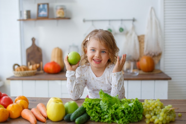 Menina na cozinha segurando maçã em casa