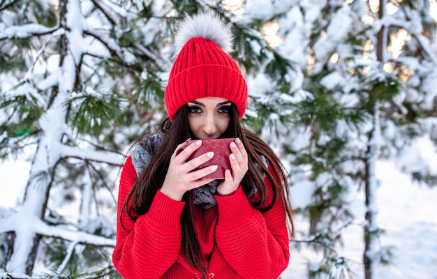 menina na floresta de inverno com uma xícara de chá quente