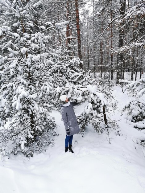 Menina na floresta de inverno entre árvores cobertas de neve.