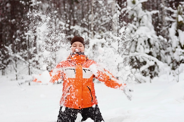 Menina na floresta de inverno lança neve e sorrisos. Cara feliz.