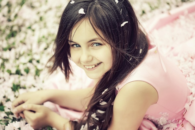 Foto menina na grama verde com pétalas