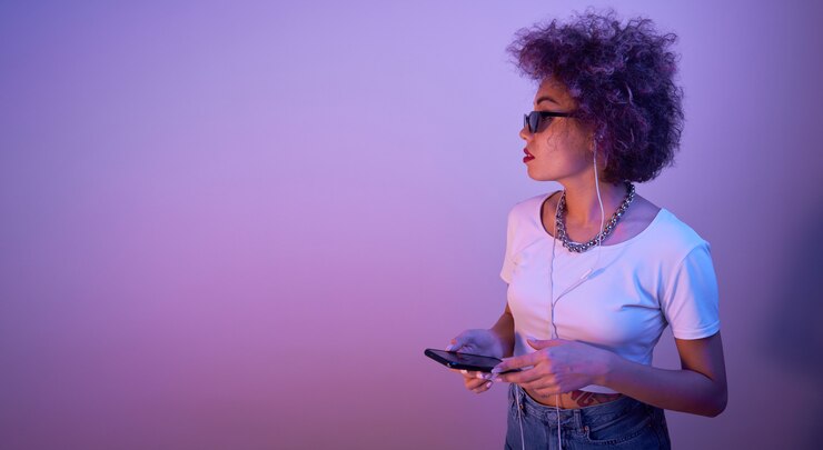 Foto menina na moda com cachos afro usando smartphone e fones de ouvido com espaço de cópia