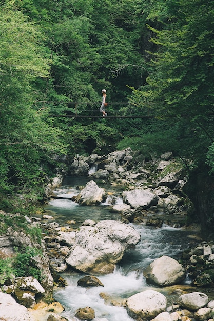 Foto menina na moda relaxante estilo de vida de viagens ao ar livre com a floresta e o rio da montanha ao fundo