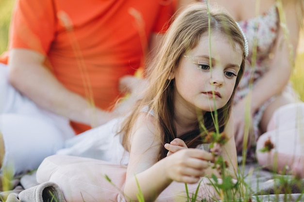 Menina na natureza brincando com grama no fundo dos pais