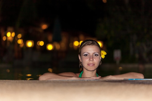 Menina na piscina ao pôr do sol