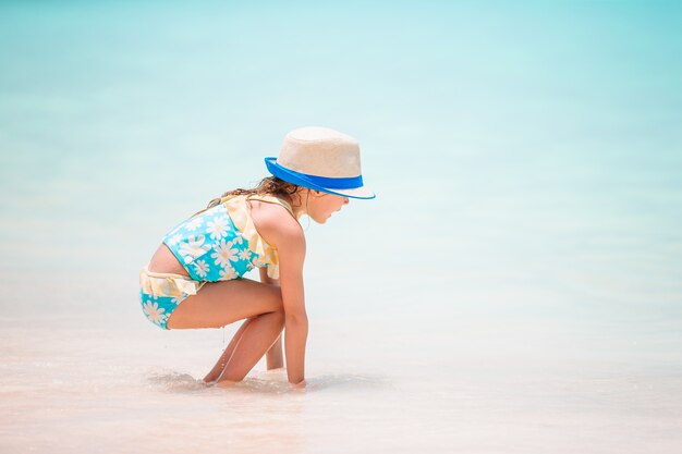 Menina na praia branca tropical, fazendo o castelo de areia