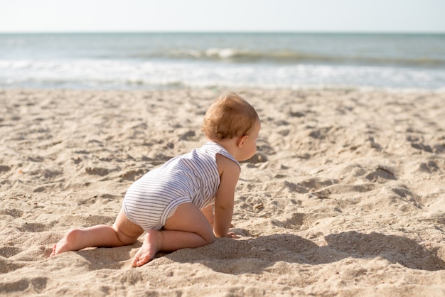 menina na praia rastejando na areia