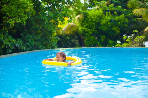 Menina nada em um anel de borracha na piscina