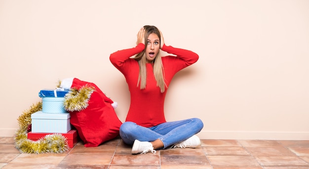 Menina nas férias de Natal, sentada no chão com expressão facial de surpresa