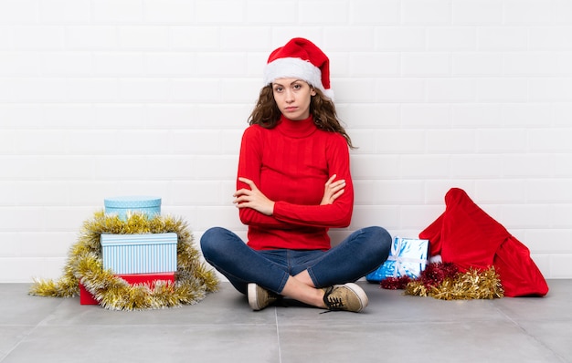 Menina nas férias de Natal, sentada no chão, mantendo os braços cruzados