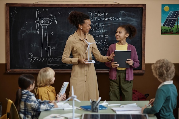 Foto menina negra com professor apresentando projeto sobre energia renovável