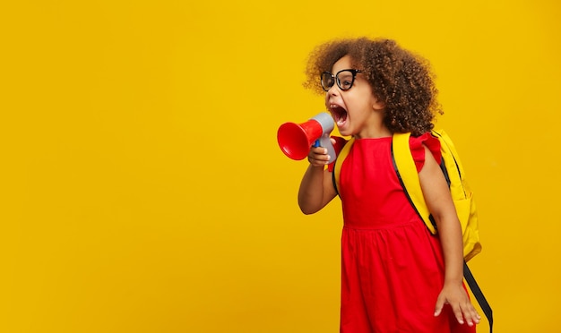 Menina negra com vestido vermelho segurando na mão e falando no megafone eletrônico cinza amarelo