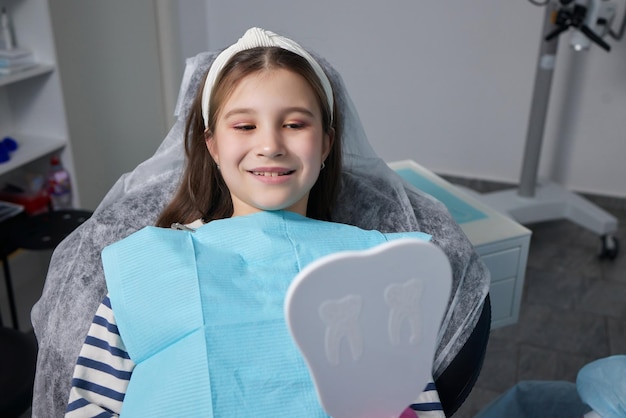 Foto menina no consultório do dentista se olha no espelho e sorri conceito de medicina e odontologia