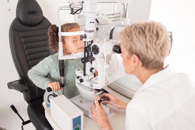 Foto menina no exame oftalmológico para visão oftalmologista verificando os olhos das crianças na sala de consulta e exame médico profissional de saúde consultando criança paciente jovem com optometrista ou médico oftalmologista