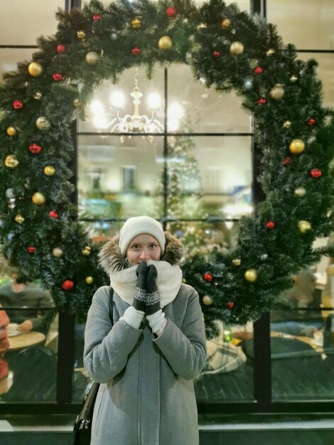 Foto menina no fundo de uma coroa de natal na rua