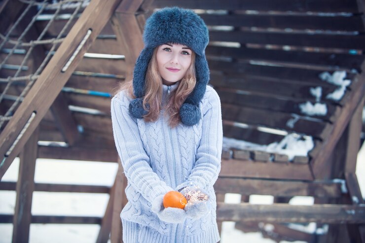Foto menina no fundo de uma paisagem de inverno segurando uma tangerina