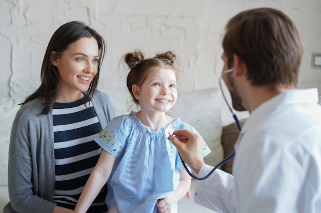 Menina no médico para um check-up. Médica ausculta os batimentos cardíacos da criança