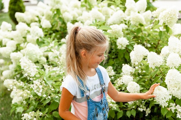 Menina no parque de hortênsias. Criança alegre. criança fareja hortênsia no jardim.