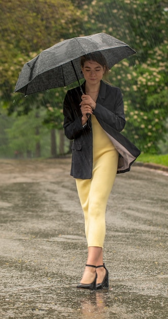 Menina no parque durante a chuva sob um guarda-chuva