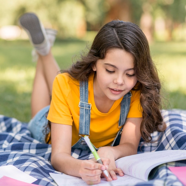 Foto menina no parque fazendo lição de casa