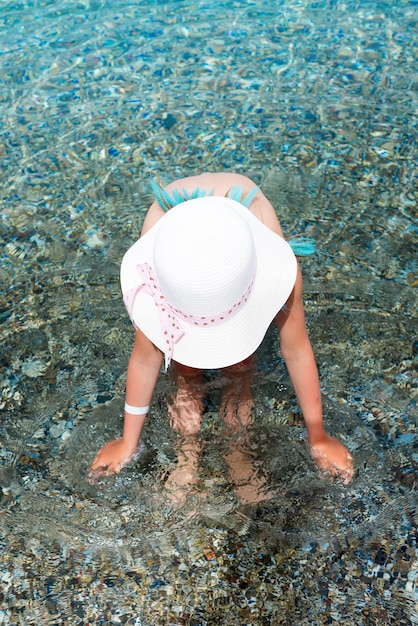 Menina no roupa de banho e chapéu branco no mar. Férias de verão no mar Egeu, ilha de Kos, Grécia