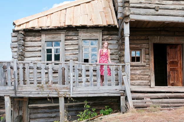 Menina no terraço de uma velha casa de madeira