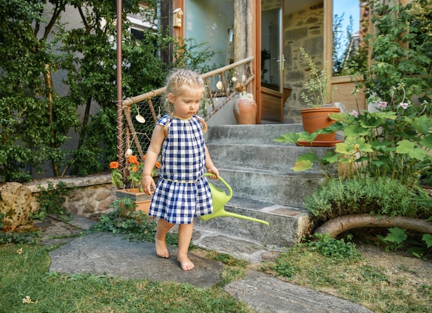 Menina num pequeno jardim com uma panela de regar verde