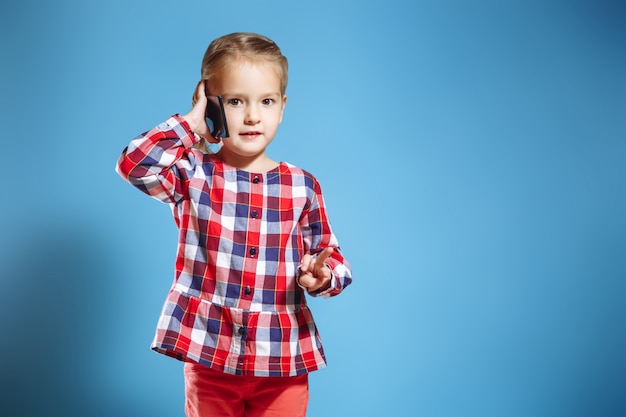 Menina ocupada falando no telefone móvel em fundo azul