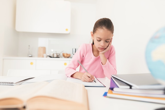 Menina olha pensativamente para o livro.