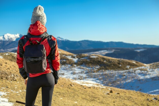 Menina olhando a paisagem no topo de uma montanha.