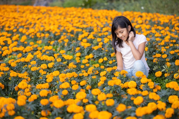 Menina olhando e sorrindo para flores de cempasuchil no campo